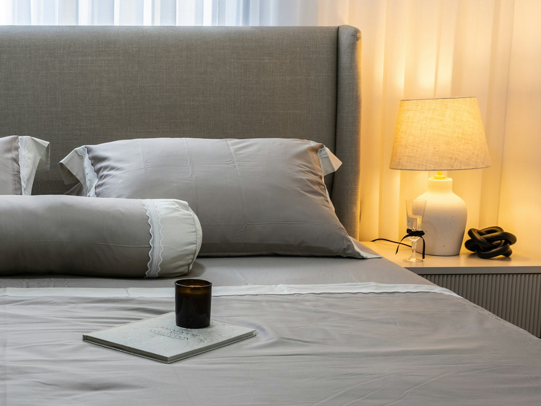 A neatly made bed with grey linens and pillows